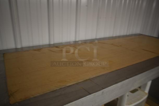 Wooden table or countertop with visible scratches and wear, set against a corrugated metal wall.