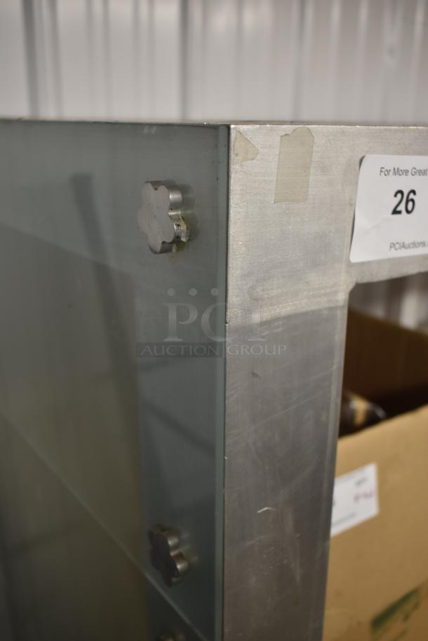 Industrial metal and glass cabinet corner, featuring clover-shaped fasteners. Tag reads: "PCI Auctions, 26." Moderate wear visible.