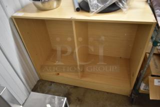 Wooden storage cabinet with two open shelves, light wood finish, minor rust mark on the bottom shelf, no visible labels.