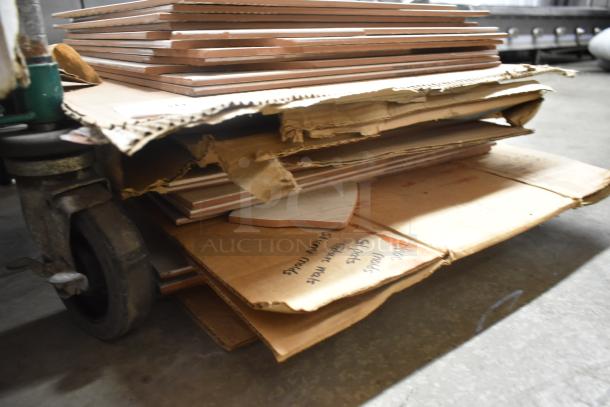Stack of ceramic tiles on a cart, mixed sizes and shapes, with visible cardboard packaging. Some handwritten notes on the cardboard.