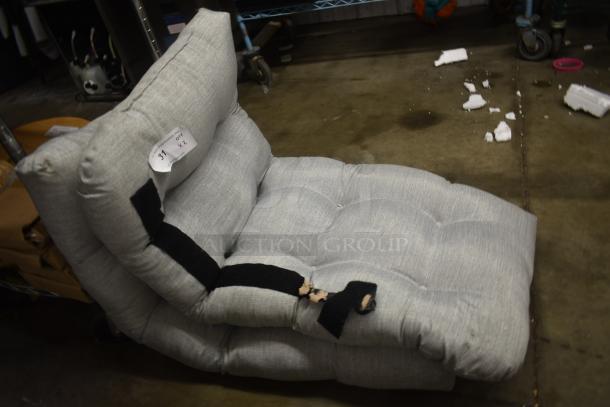 Gray tufted lounge chair with black straps, showing signs of wear and tear. A label reads "Lot 37 x2."