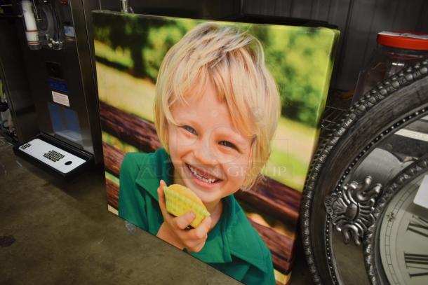 Canvas print featuring a smiling child holding a cupcake. Vivid colors, outdoor background. Excellent condition.