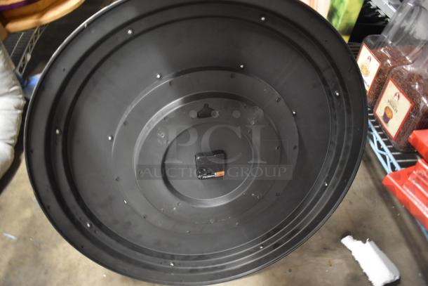 Large black industrial fan blade, circular with concentric rings, screws visible, moderate wear; Duracell battery label.