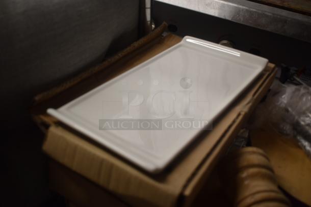 White rectangular ceramic serving platter on a cardboard box. Smooth surface, excellent condition, ideal for dining use.