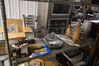Metal storage shelf with various items including light bulbs, wooden tree decorations, and a plastic-wrapped item labeled "34."