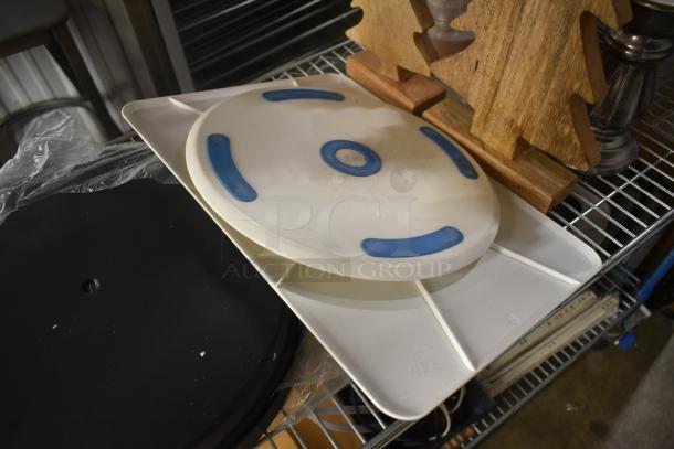 Rotating cake stand with blue grips on a white base, used condition. Features round platform on square base, no visible branding.