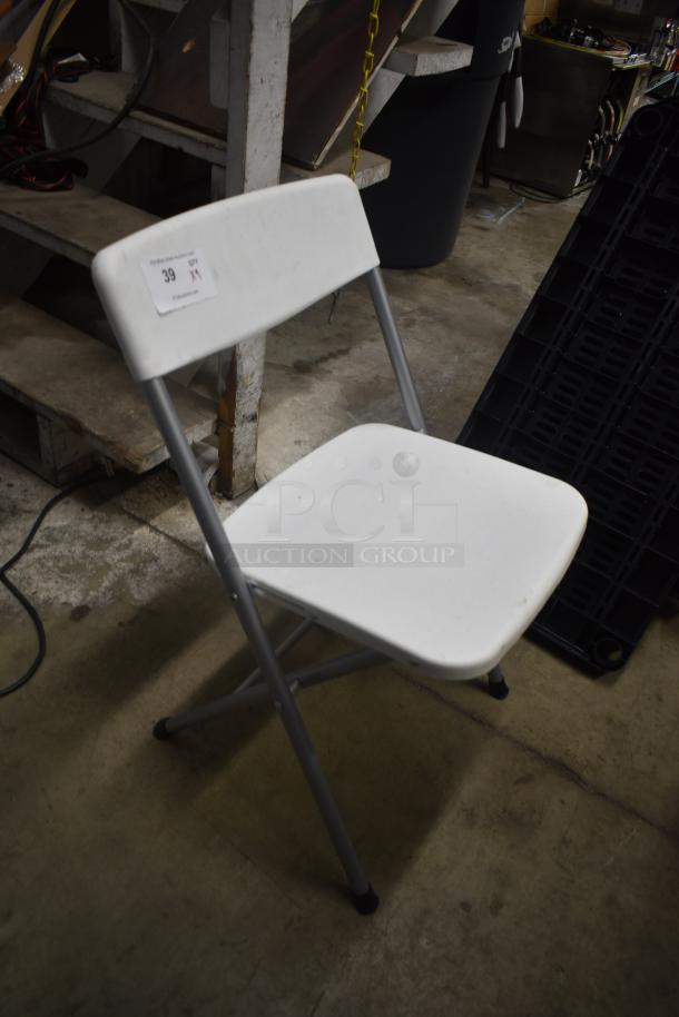 White folding chair with metal legs, in used condition. Auction tag numbered 39 indicates item for sale.