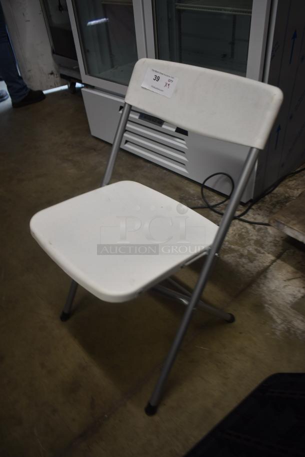 White folding chair with metal legs, slightly worn condition. Tag marked "39" and "Qty 1," indicating auction item details.