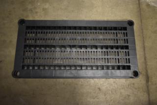Black plastic industrial grate, rectangular with slots, in good condition. Features mounting holes at corners.