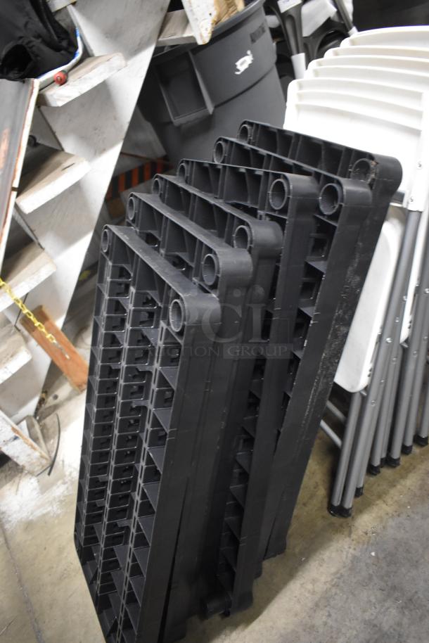 Stack of black plastic pallet tops, ribbed design, stacked vertically. Appears to be in good condition.