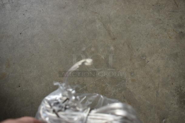 Coiled clear cable wrapped in plastic on a concrete background. Condition appears new, possibly suitable for electronics.