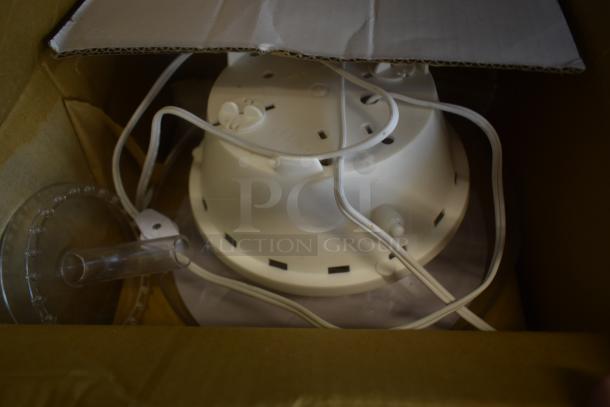 White plastic appliance with cords and transparent tube, packaged in a cardboard box. Appears new, condition unspecified.