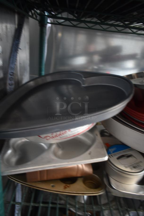 Heart-shaped cake pan, dark non-stick surface, good condition. Accompanied by a muffin tray and measuring cups.