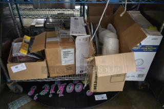 Various open boxes on a metal shelf containing assorted items like printer sheets and clear slotted flat lids. Labels indicate content details.