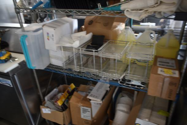 Industrial storage shelf with metal baskets, plastic containers, cardboard boxes, and cleaning supplies. Used condition.