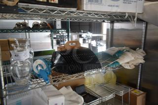 Shelving unit with mixed kitchen items: glass jars labeled "47," a blue mop head, black plastic holders, and kitchen cloths.