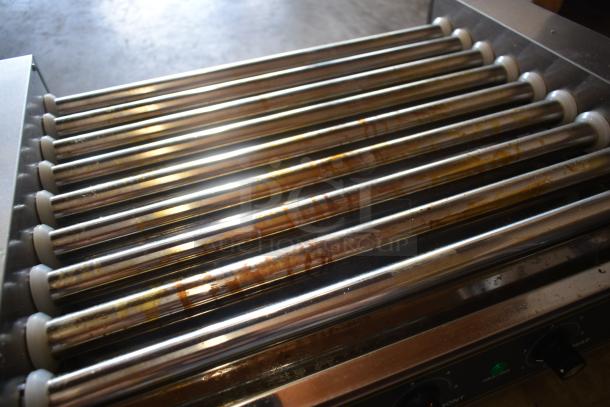 Stainless steel hot dog roller grill, used condition, multiple rollers, visible heating controls, signs of wear.