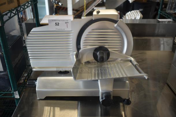 Industrial meat slicer, silver, ribbed design, good condition, includes label with auction info, sturdy base, manual operation.