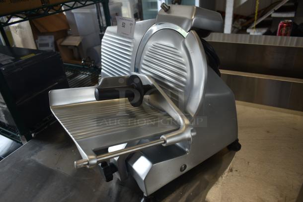 Commercial meat slicer in good condition, stainless steel with safety guard and thickness adjustment knob. Auction tag reads "52."