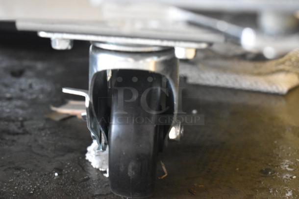 Close-up of a black swivel caster wheel with metal bracket, in good condition, mounted on a flat surface.