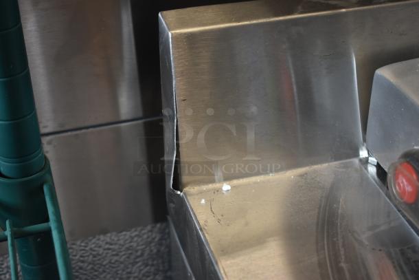 Stainless steel countertop edge with visible dent and scratches, minor wear; potential use in commercial setting.