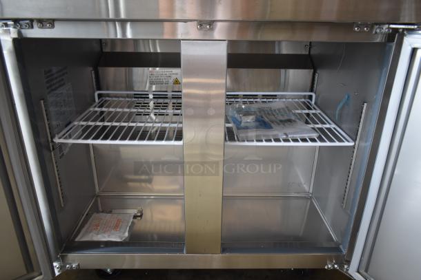 Commercial stainless steel refrigerator interior with wire shelves. New condition with instruction labels visible.