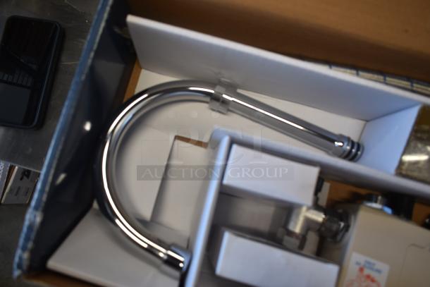Chrome kitchen faucet in original packaging, new condition, with mounting hardware included.