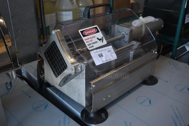 Commercial meat slicer with stainless steel body, clear protective cover, and warning label. Auction tag number 66 visible.
