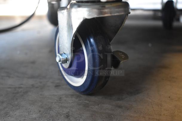 Industrial caster wheel with blue rubber tire and metal bracket, featuring a locking mechanism. Appears in excellent condition.