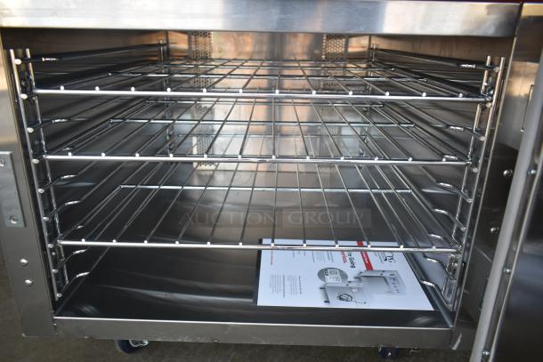 Stainless steel commercial oven interior with adjustable wire racks, manual visible on lower rack, in excellent condition.