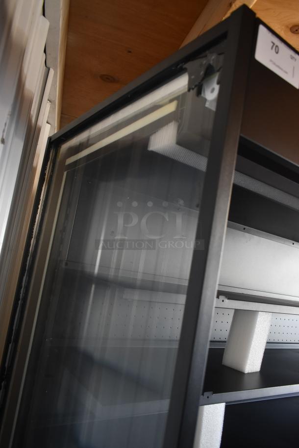 Glass display cabinet with black metal frame, shelves supported with foam blocks. Upper corner shows slight damage. Number tag 70 visible.