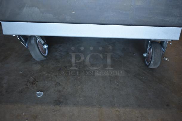 Metal cart base with swivel casters on concrete floor; good condition, sturdy construction.