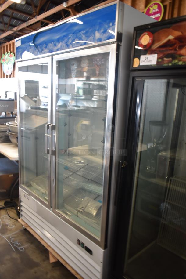 Commercial glass-door refrigerator with stainless steel frame, dual sliding doors, and visible shelving. Clean, good condition.