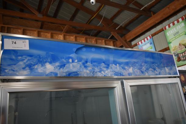 Commercial glass door freezer with ice-themed panel, auction tag 74, good condition, dual doors, silver frame.