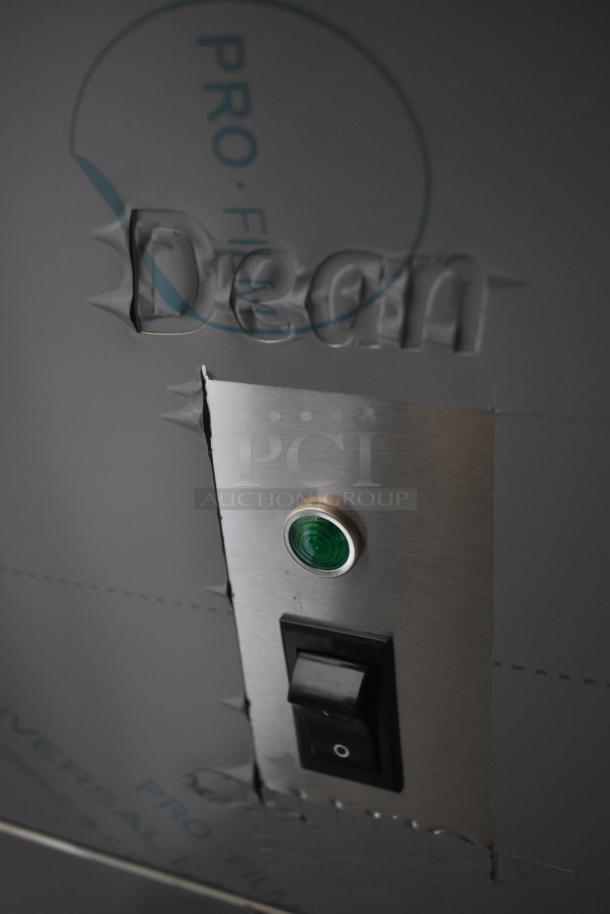 Stainless steel panel with green button and black switch. "Dean" partially visible on protective film. Good condition.