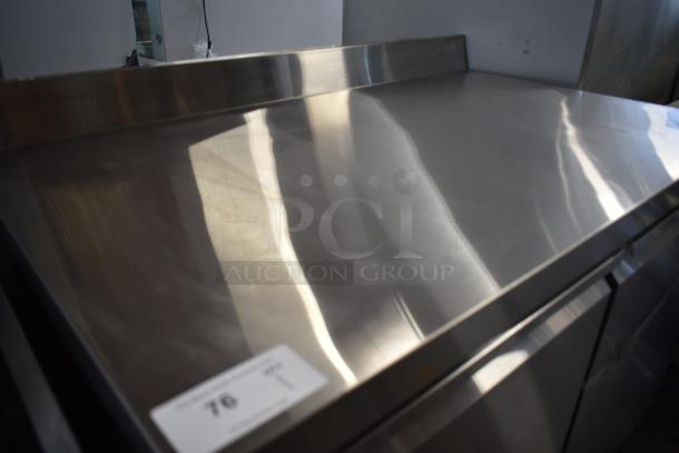 Stainless steel countertop with backsplash, in excellent condition, reflective finish. Auction tag indicates item number 76.