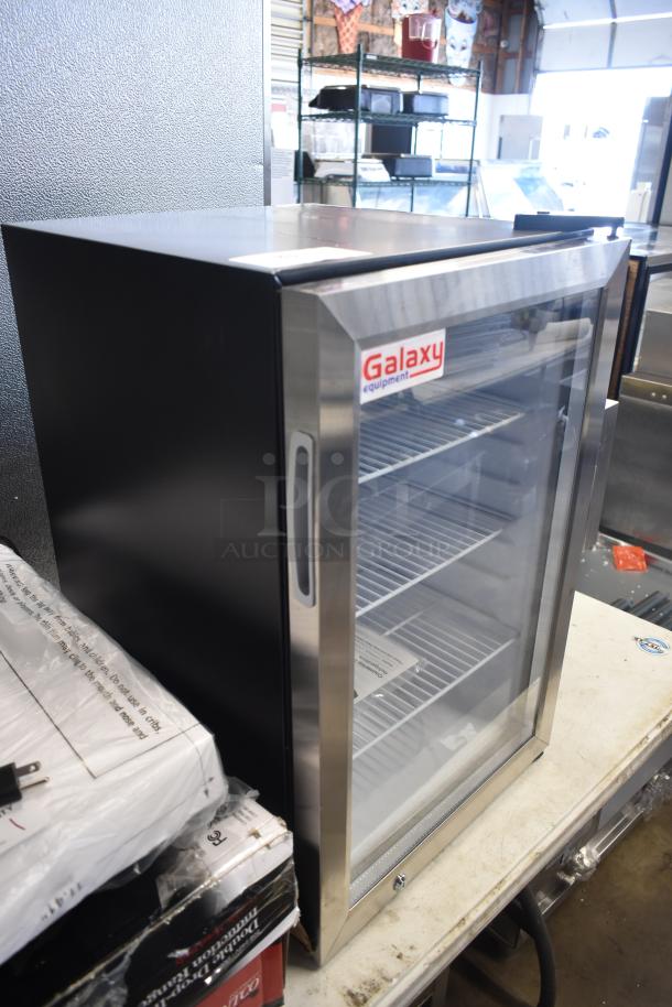 Galaxy refrigerator with glass door, stainless steel frame, and multiple shelves in good condition. Labels indicate "Galaxy Equipment."