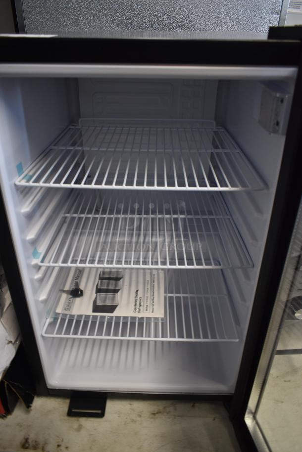 Stainless steel mini fridge with three wire shelves in new condition, includes a user manual and a metal tool inside.
