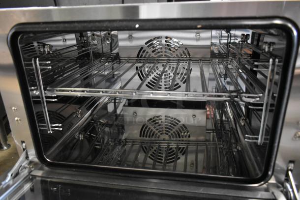 Stainless steel convection oven interior with multiple racks and rear fan, indicating spacious and efficient cooking.