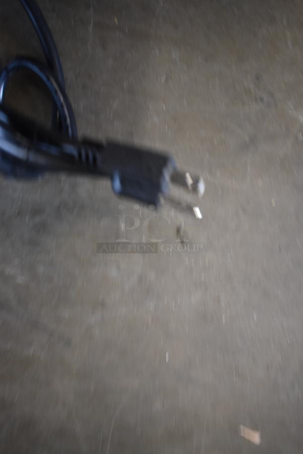 Blurry image of a black electrical power cord with a two-prong plug. Condition and additional details are unclear.