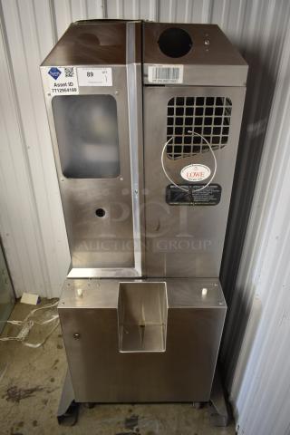 Stainless steel ice machine with Asset ID tag 7712954189 and Lowe service label. Ventilation grate and chute visible.