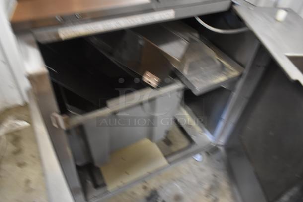 Industrial metal cabinet with compartments, open door revealing storage bins, worn condition, no visible markings or labels.