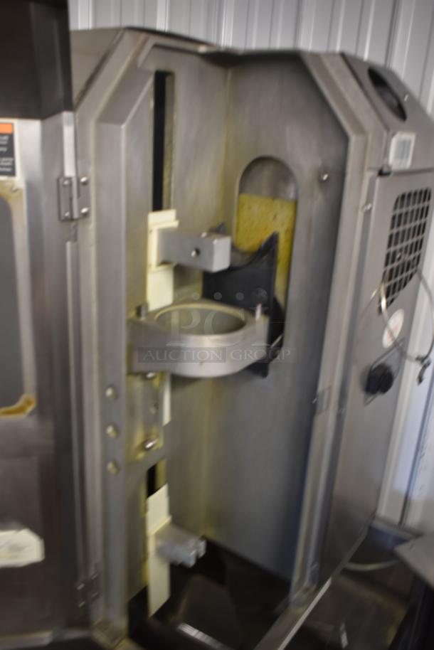 Industrial metal processing machine, interior view. Features include metal casing, control dial on the right, wear and residue present.