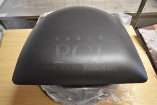 Black leather seat cushion in excellent condition on a wooden surface, possibly for a chair or stool.