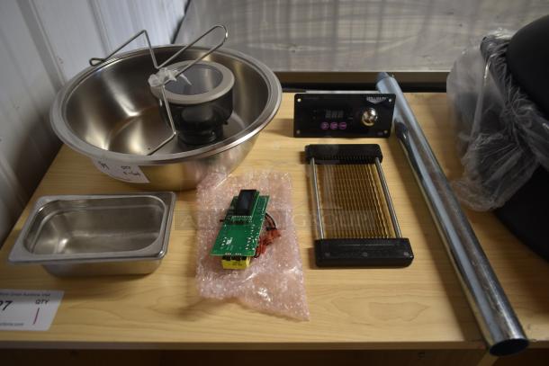 Assorted kitchen equipment including stainless steel bowls, slicer, digital display unit, and metal tube on wooden surface.