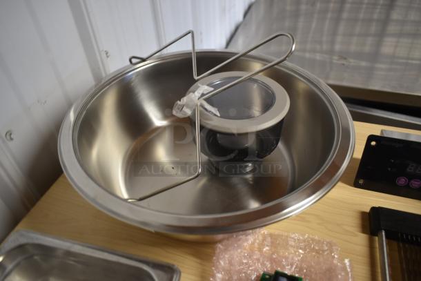 Stainless steel mixing bowl with attached wire holder and lid, in excellent condition, placed on wooden surface.