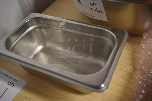 Stainless steel rectangular baking tray with minor wear, displayed on a wooden surface. Visible auction label denotes quantity.
