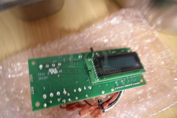 Electronic circuit board with LCD screen, partially wrapped in bubble wrap, showing "Elkay 802386." Appears new.