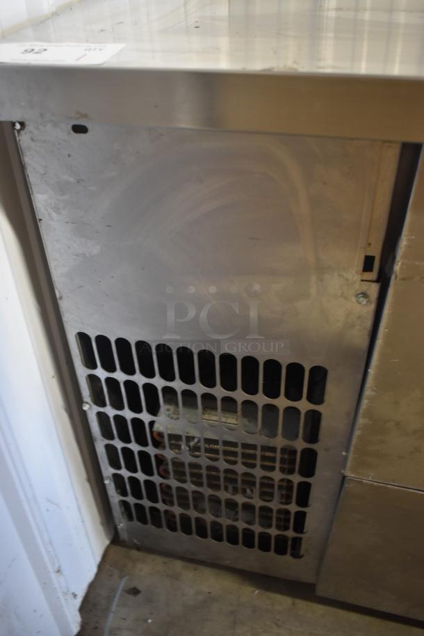 Stainless steel commercial refrigerator panel with vented grille, industrial-grade, moderate wear, auction tag number 92 visible.