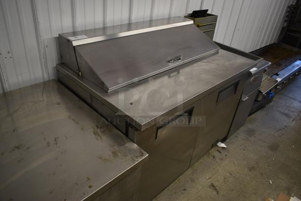 Stainless steel commercial sandwich prep table with lid, dual storage compartments, and visible signs of use. Serial number tag attached.